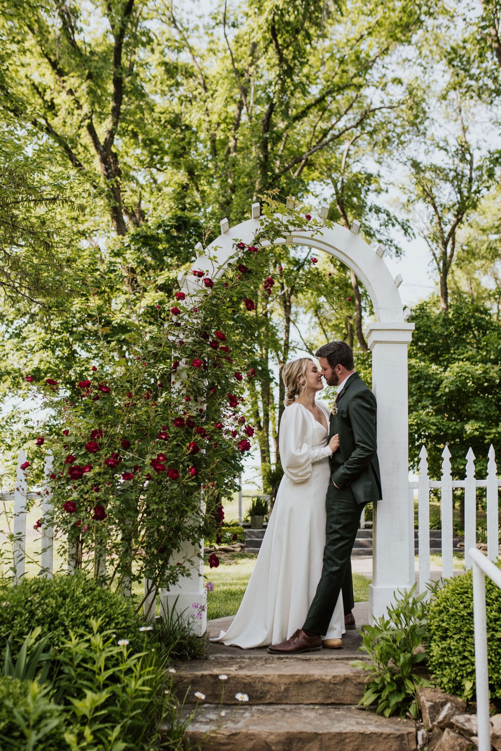 Bride and groom portrait taken under a flowery arch outside Holy Trinity Catholic Church Weston MO