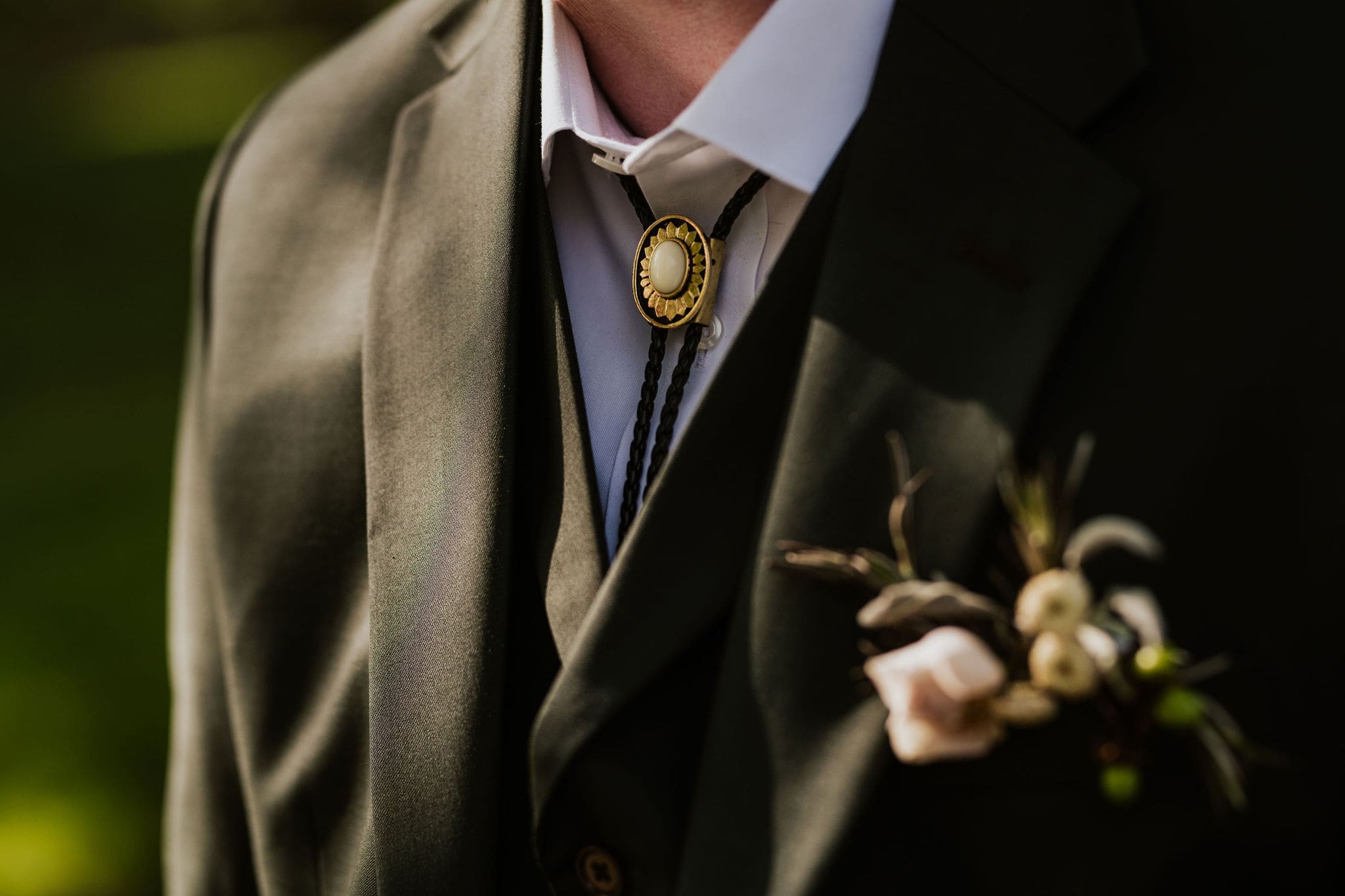 Close up of groom's green suit and bolo tie