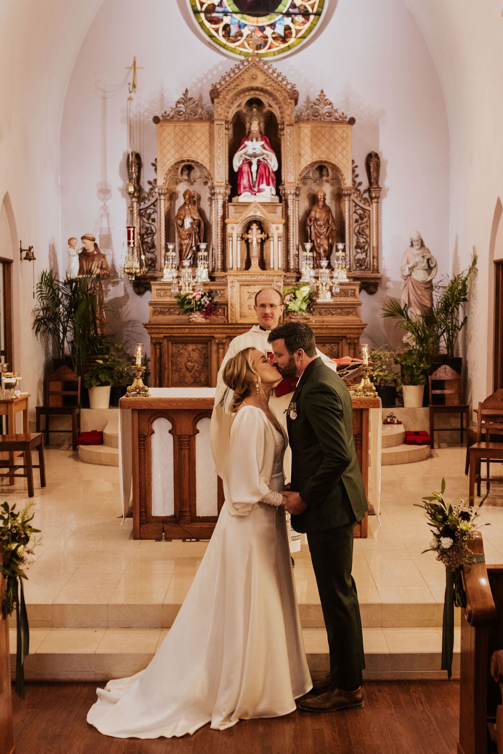 Bride and groom share a first kiss during their wedding ceremony at Holy Trinity Catholic Church Weston MO