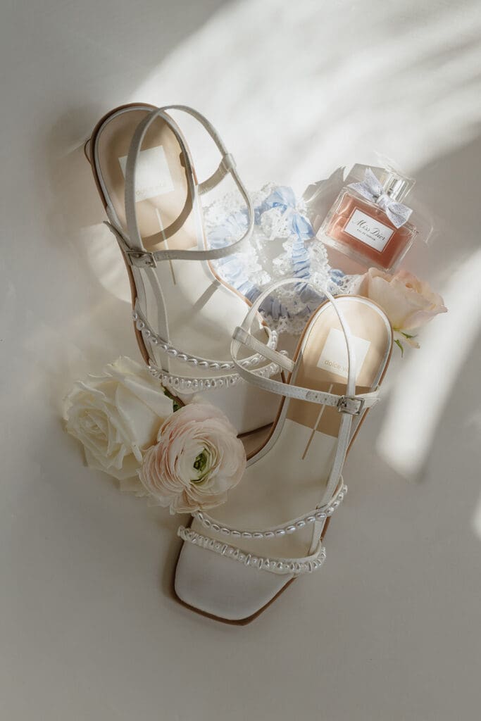 White bridal heels with a blue lace garter and Miss Dior perfume, wedding at Our Lady of Guadalupe Catholic Church St. Joseph MO