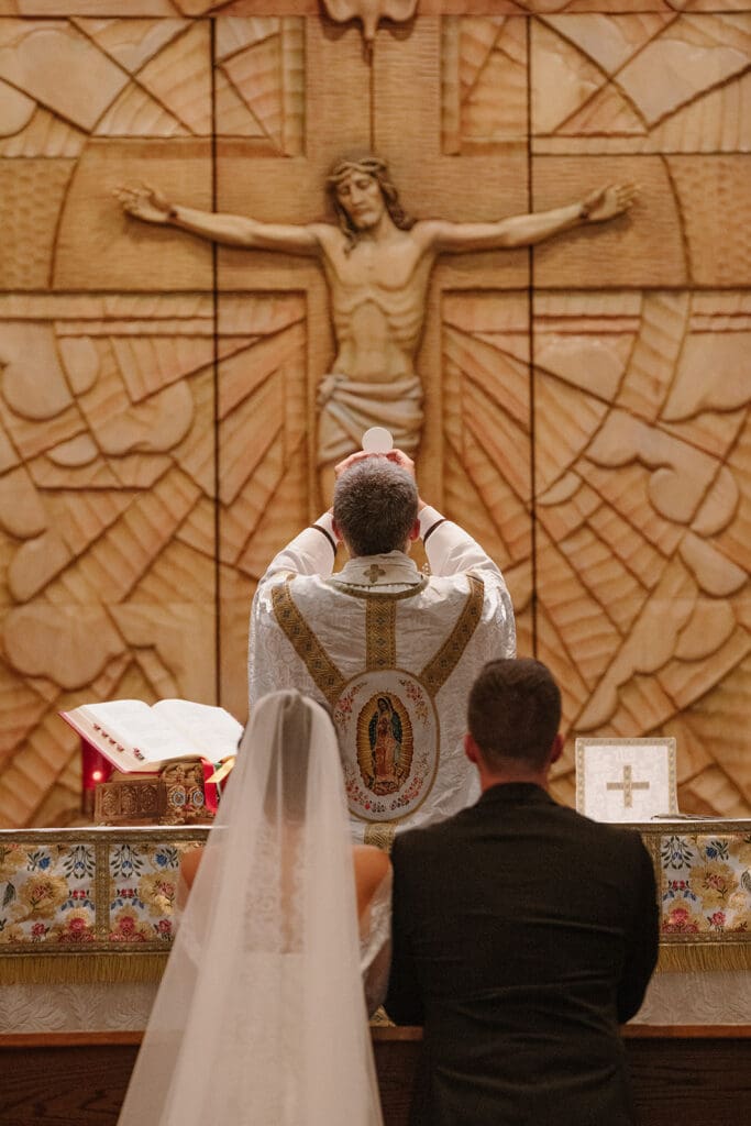 Priest elevating the host during Mass at a wedding at Our Lady of Guadalupe Catholic Church St. Joseph MO