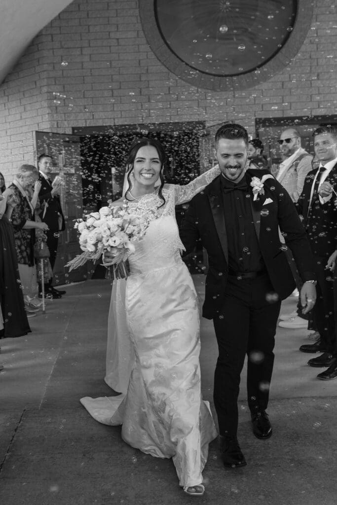 Bride and groom exiting their wedding ceremony through bubbles at Our Lady of Guadalupe Catholic Church