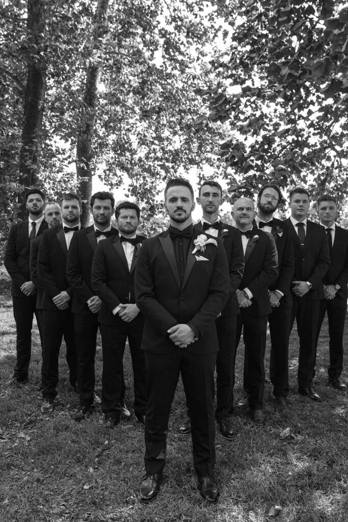Black and white group photo of groom and groomsmen in black tuxedos