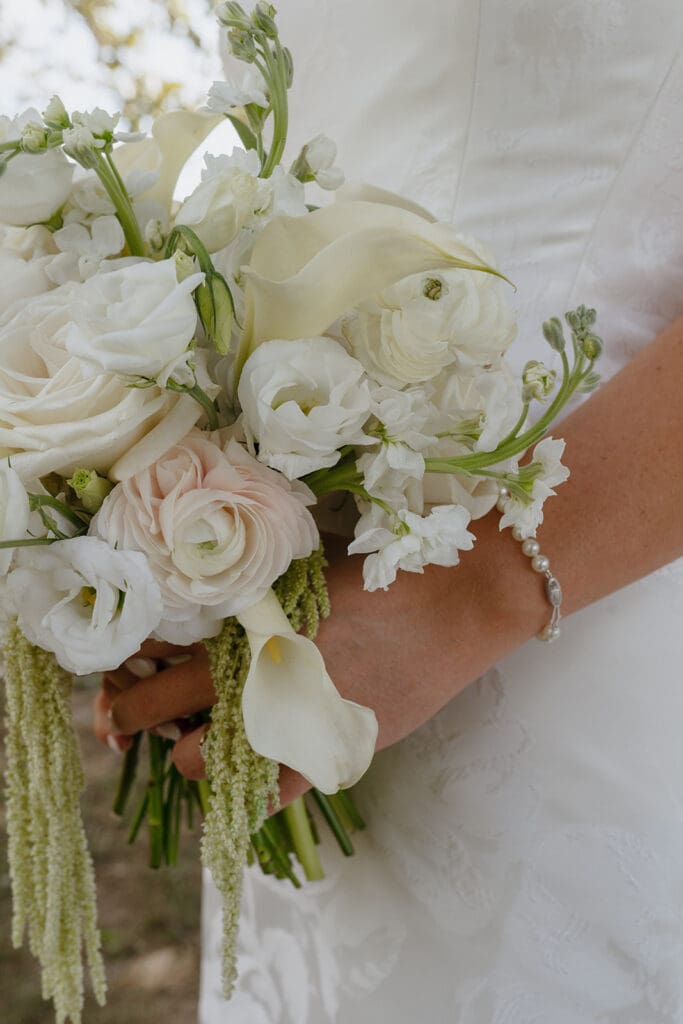 Close-up of white and blush bridal bouquet with pearl bracelet