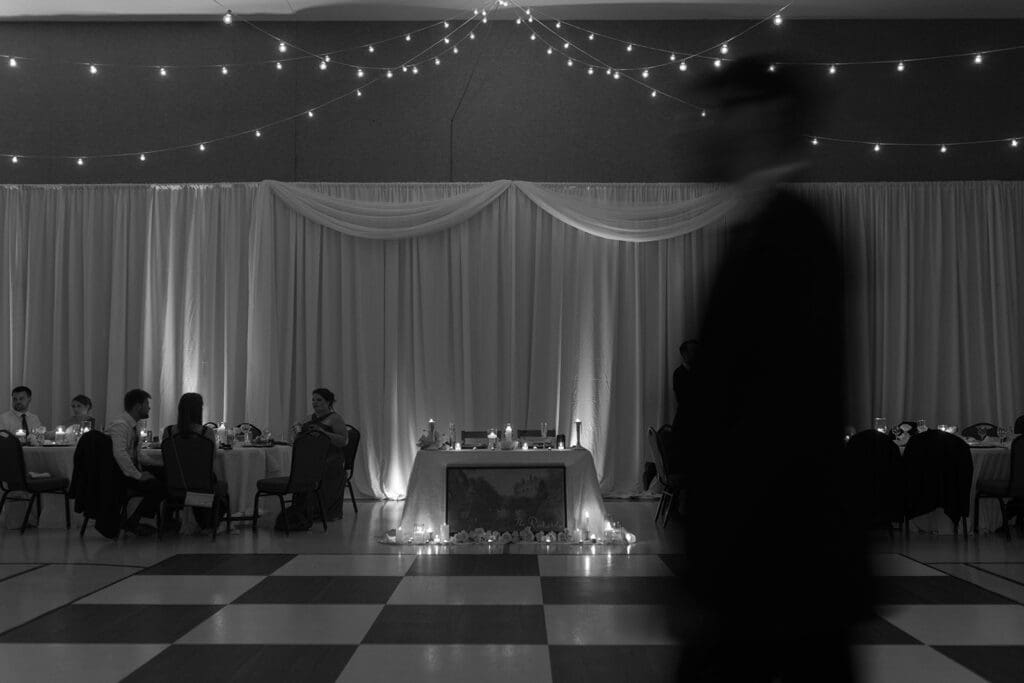 Black and white photo of Summer's Hall decorated for a wedding reception with string lights and candles