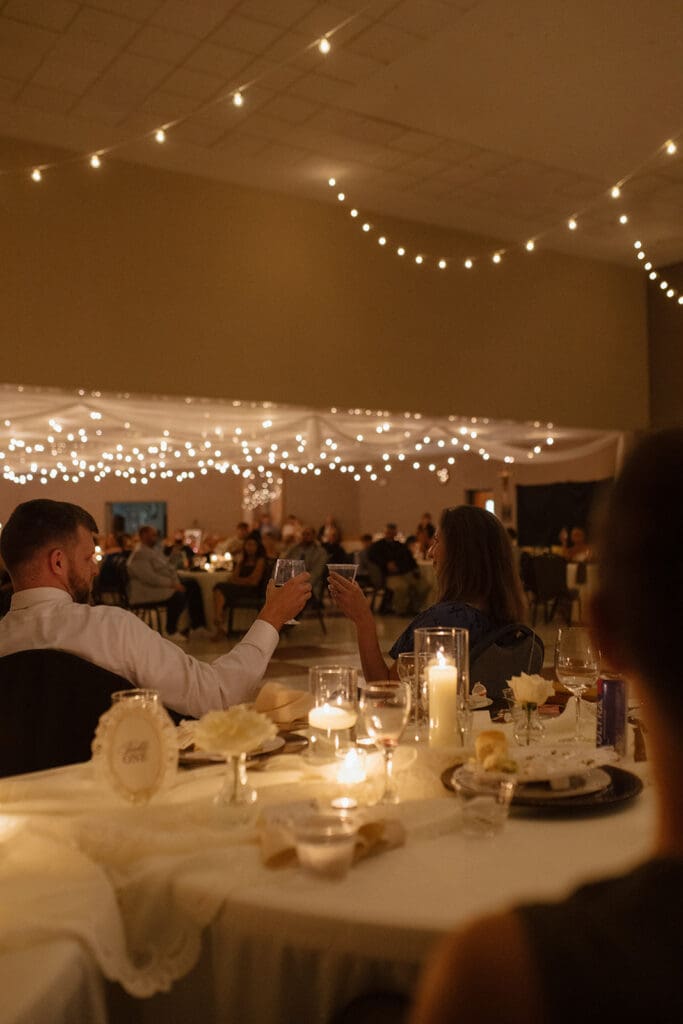 edding guests raising a toast at a candlelit reception table