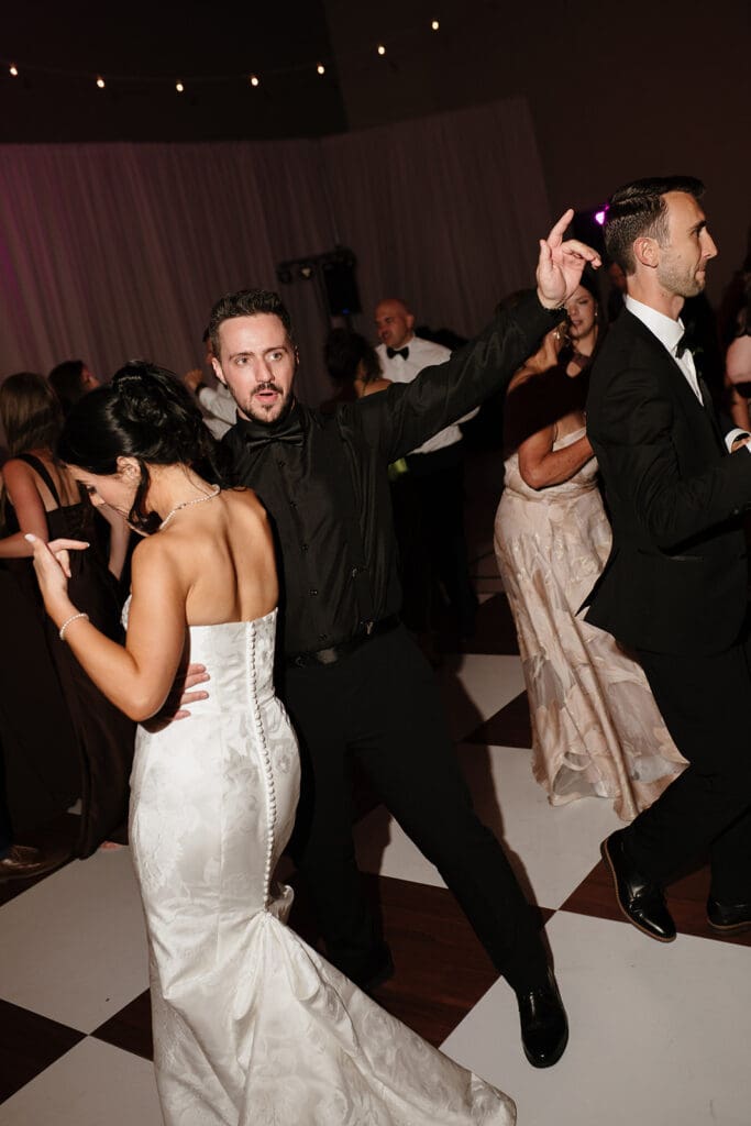 Wedding guests dancing on a checkered dance floor at the reception