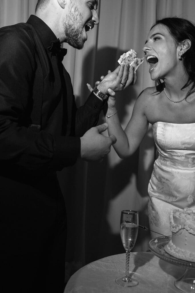 Black and white photo of bride and groom feeding each other wedding cake
