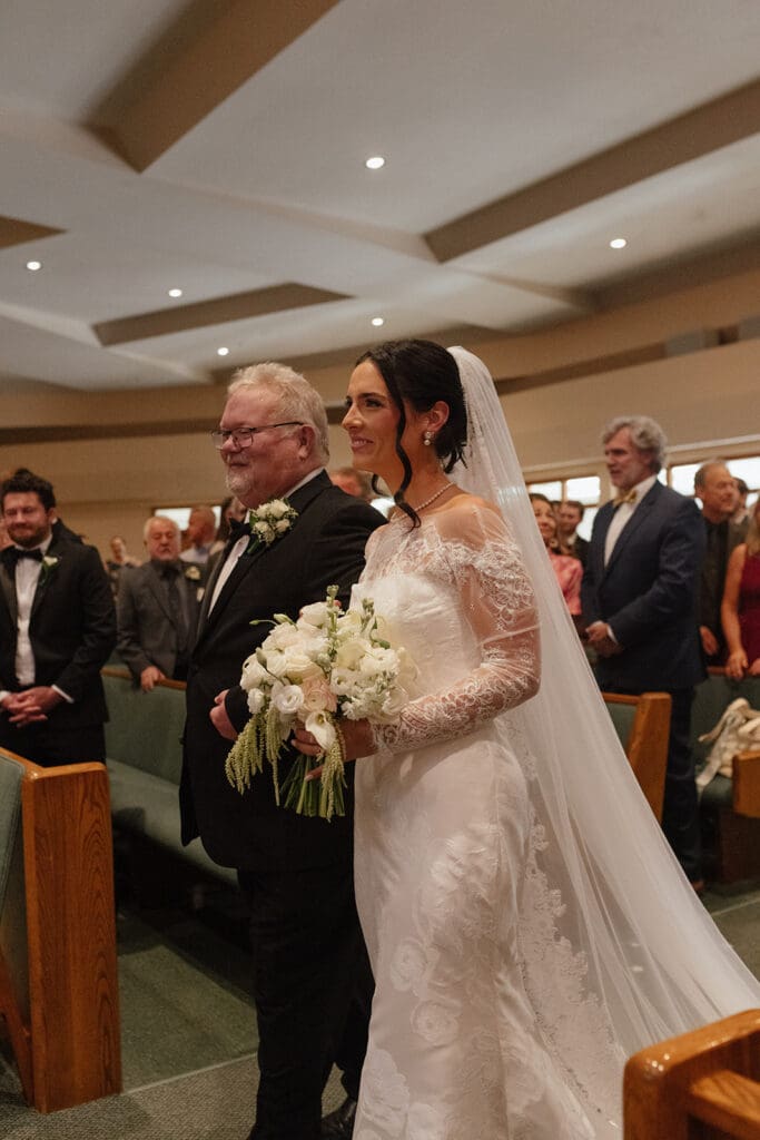 Bride walking down the aisle with her father at Our Lady of Guadalupe Catholic Church in St. Joseph Missouri