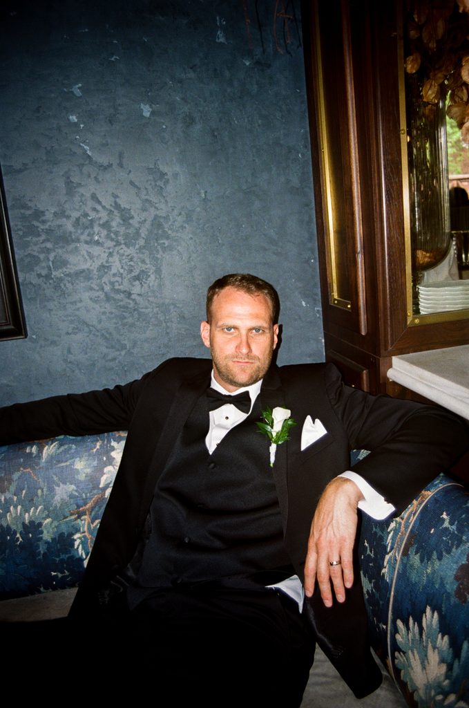 a film photo with flash of a groom sitting on a couch