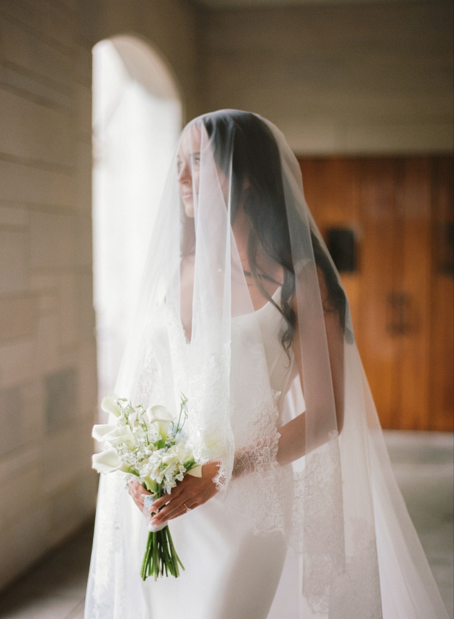 a film photo of a bride with the veil over her face